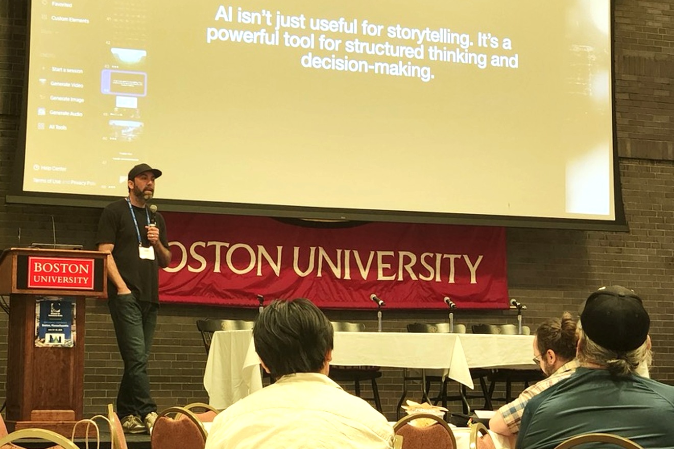 Erich Archer on stage with a microphone at Boston University, at the Alliance for Community Media National Conference